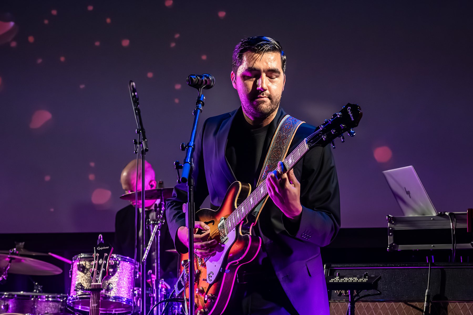 Lars op gitaar in roze theaterlicht